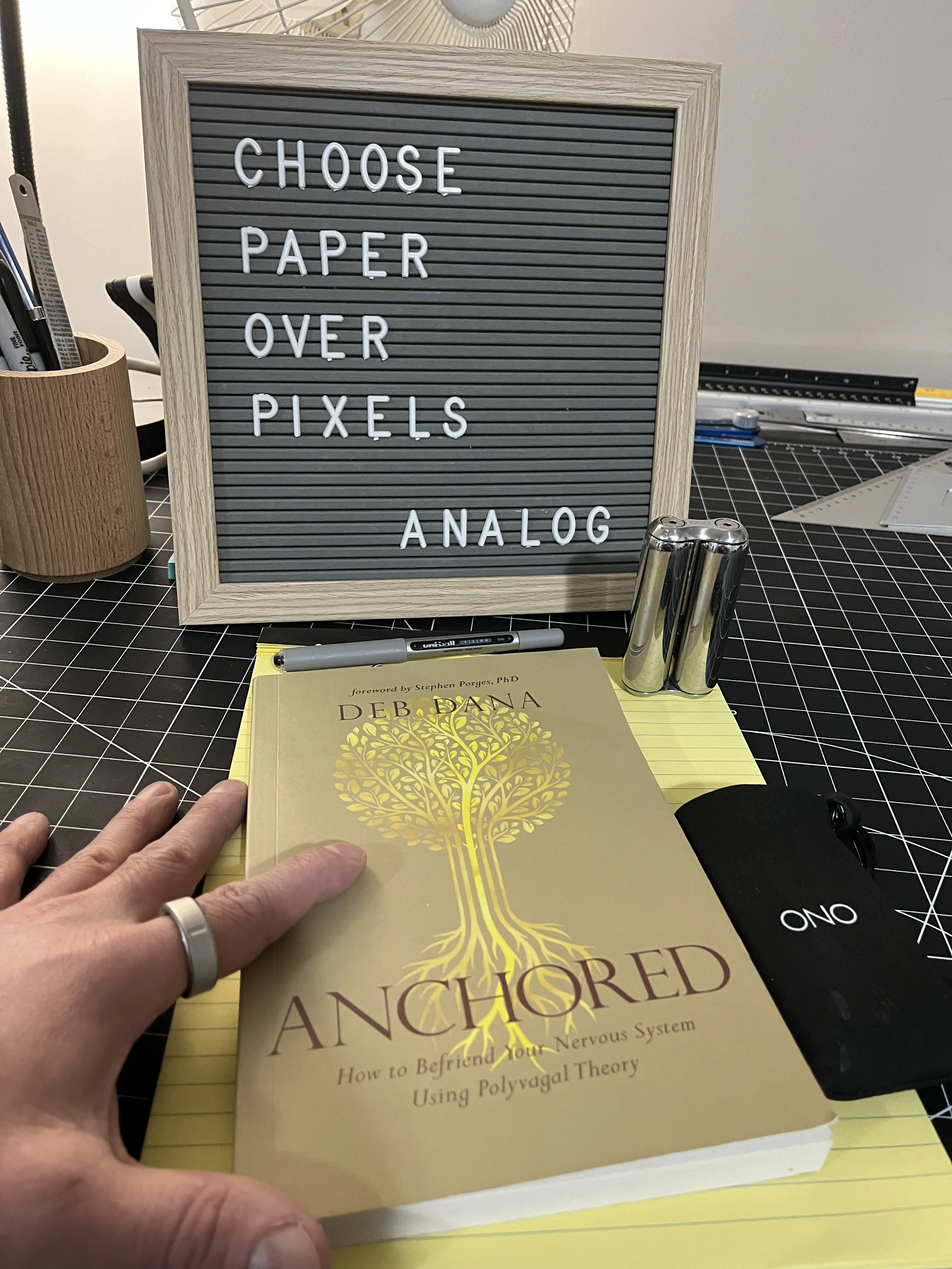 My Oura Ring 4 on my hand, and my copy of Anchored by Deb Dana